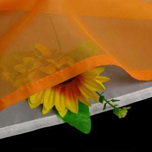 Detailaufnahme des orangefarbenen Stoffs mit halbdurchsichtiger Konstruktion. Sie können die Sonnenblumen darunter, die Mikronetzkonstruktion und die orangefarbene Verkleidung sehen.