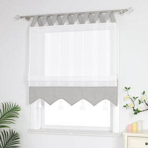Graue und weisse Raffrollo Gardine mit Schlaufen dekorativen Quasten und geschwungenem Saum halb hochgezogen, Seitenansicht eines weißen Raffrollos mit Quasten und Schlaufen – halb geschlossen, sodass die Fenster nicht vollständig bedeckt sind, neben Grünpflanzen und duftenden Ornamenten.