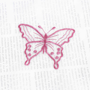 Nahaufnahme einer lila Schmetterlingsstickerei, die auf einem transparenten weißen Stoff flach ausgebreitet liegt. Die lila Schmetterlinge sind sorgfältig in das Gewebe eingearbeitet.