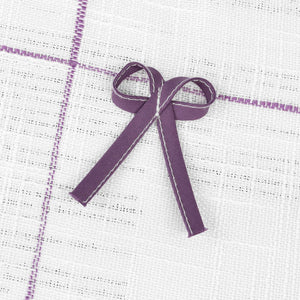 Dies ist eine violette Schleife, die an einem weißen Gewebe mit violetten Linien befestigt ist.