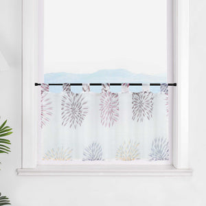 Die transparente Scheibengardine mit lila Feuerwerksmotiven hängt vor einem Fenster. Die weiße Wand im Hintergrund hebt die lila Muster des Feuerwerks hervor und verleiht dem Raum eine festliche und elegante Stimmung.