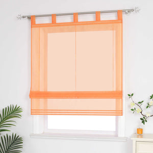 Halbtransparenter oranger Raffrollo hängt vor dem Fenster und sorgt für eine helle, luftige Atmosphäre. Daneben setzen grüne Pflanzen dekorative Akzente. Seitliche Ansicht.