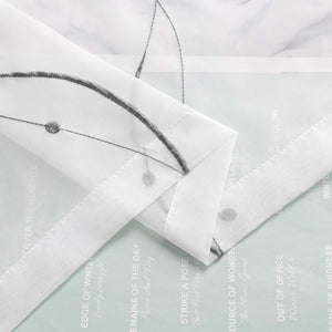 Ein weisser, duenn gewebter Stoff mit schmalem Wellenlinienmuster ist mehrfach gefaltet. Im Hintergrund befindet sich Papier mit aufgedrucktem Text und Motiven.