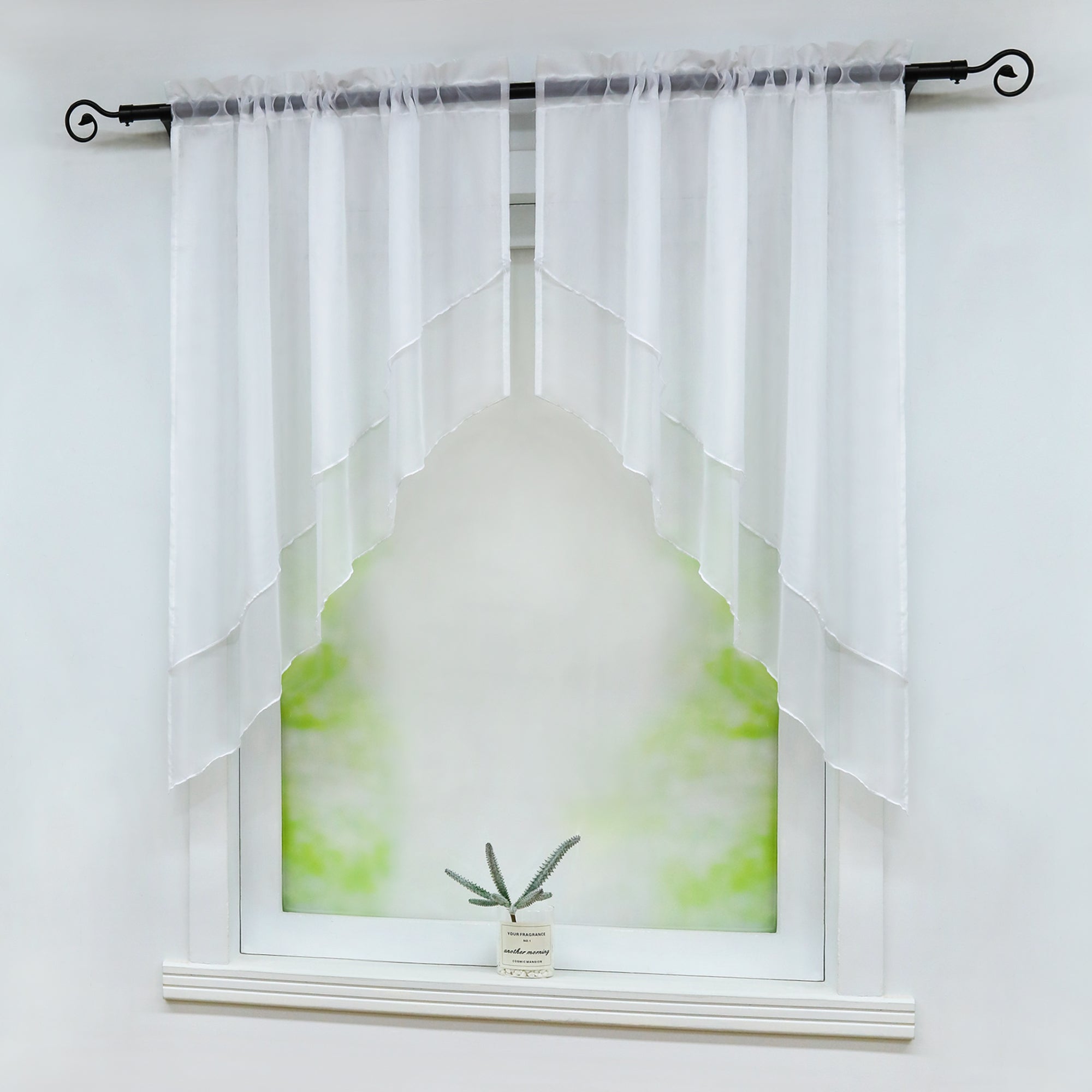 Seitliche Ansicht eines Fensters mit weißen, halbtransparenten Vorhängen, die symmetrisch diagonal geschnitten sind. Eine kleine grüne Pflanze steht dekorativ auf der Fensterbank vor einem weichen, grünen Hintergrund.
