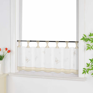 Seitliche Ansicht eines beige transparenten Kurzvorhangs mit dekorativen Perlen an den Aufhängeschlaufen und Schmetterlingsmuster auf der Oberfläche. Der Vorhang hat ein beiges Dekoband am unteren Rand und ist vor einem Fenster mit einem Schrank und Blumen als Dekoration aufgehängt.