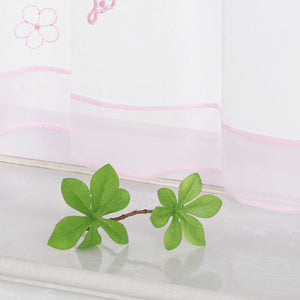 Nahaufnahme des unteren Teils eines rosa transparenten Vorhangs mit Schmetterlings- und kleinen Blumenmustern. Der Vorhang ist mit einem rosa Dekoband am unteren Rand verziert.