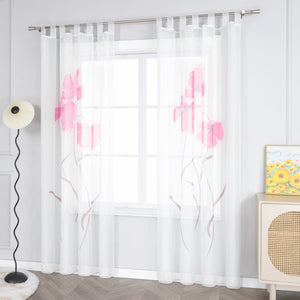 Das Bild zeigt einen weißen Voile-Vorhang mit einem Muster aus rosa Blumen und braunen Zweigen, der mit Metallringen an einer Stange aufgehängt ist. Neben dem Fenster steht eine Stehlampe mit einem weißen Lampenschirm. Daneben befindet sich ein heller Schrank mit einem gewobenen Musterelement auf der Oberfläche, auf dem ein Gemälde in Gelbtönen platziert ist.