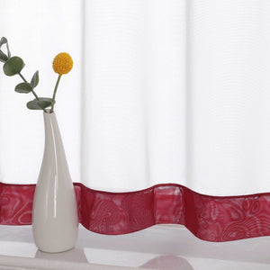 Die Unterkante des Vorhangs wird im Detail gezeigt, mit einem weinrot Dekorband als stilvollem Akzent. Ein Vase im Vordergrund ergänzt die Szene und fügt dem Raum eine harmonische, dekorative Note hinzu, die den eleganten Look des Vorhangs unterstreicht.